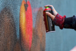 Dłoń trzymającą farbę w aerozolu i malująca po ścianie 
