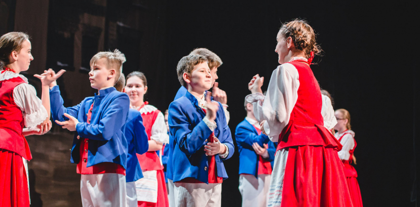 dzieci w strojach regionalnych tańczą na scenie