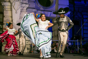 Chłopiec i dziewczynka w meksykańskich strojach regionalnych tańczą na scenie