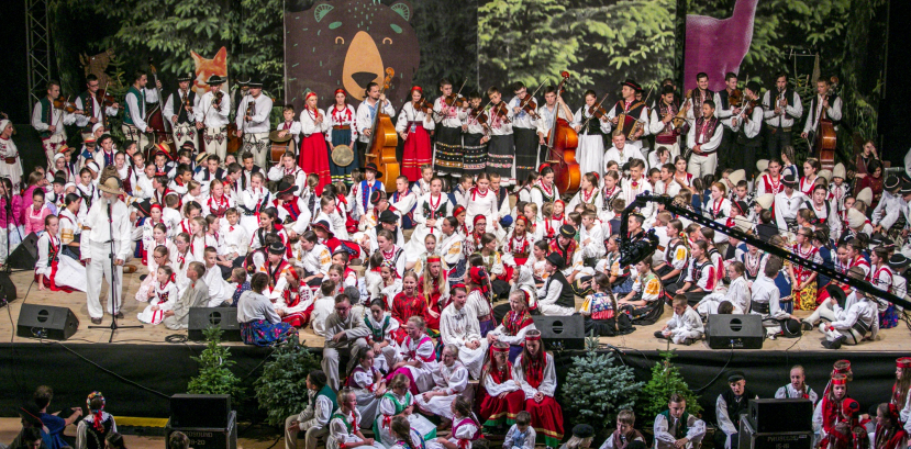 Ogromna ilość dzieci siedzi na scenie i schodach do niej prowadzących