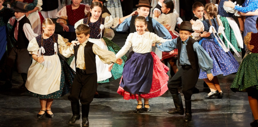 Dzieci w węgierskich strojach regionalnych tańczą na scenie