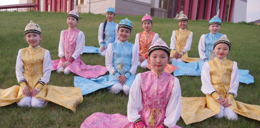 Dziewczynki w rosyjskich regionalnych sukienkach siedzą na trawie