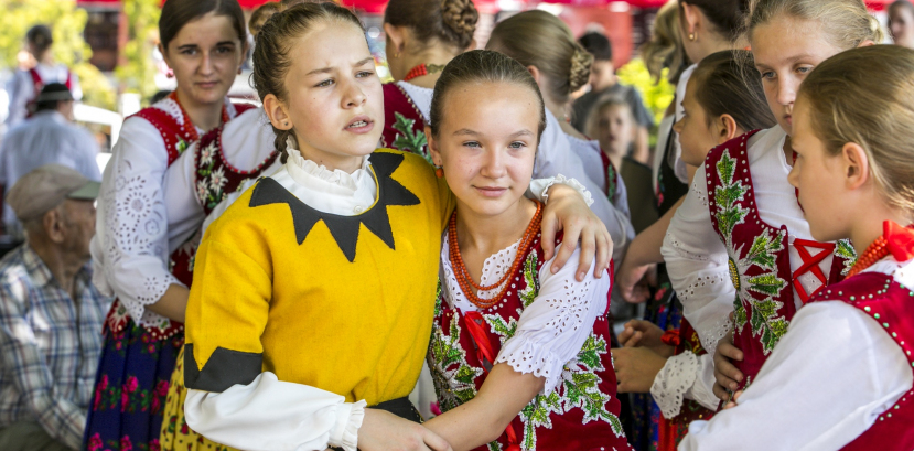 Dziewczynki w strojach ludowych przytulają się.