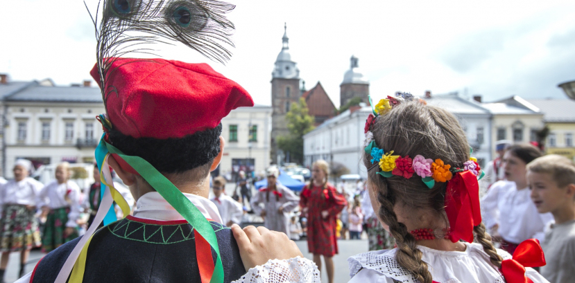 Chłopak i dziewczyna tyłem w strojach ludowych.