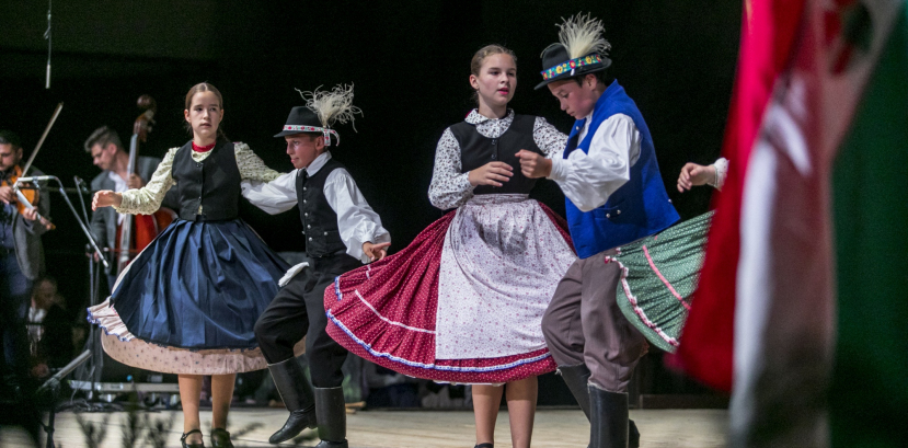 Dzieci w węgierskich strojach regionalnych tańczą na scenie