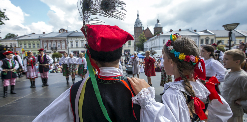 Dziewczynka i chłopiec w krakowskich strojach regionalnych stoją tyłem na scenie