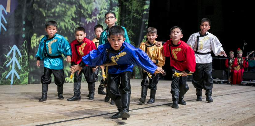 dzieci w barwnych, regionalnych strojach tańczą na scenie