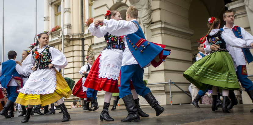 Dzieci w strojach ludowych tańczą na płycie rynku.