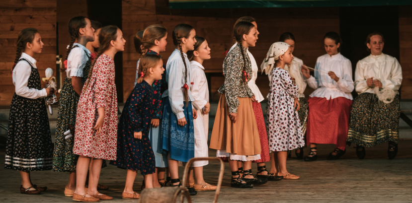 dzieci w regionalnych strojach stoją na scenie i patrzą się w jednym kierunku