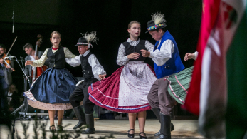 Dzieci w węgierskich strojach regionalnych tańczą na scenie