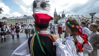 Dziewczynka i chłopiec w krakowskich strojach regionalnych stoją tyłem na scenie