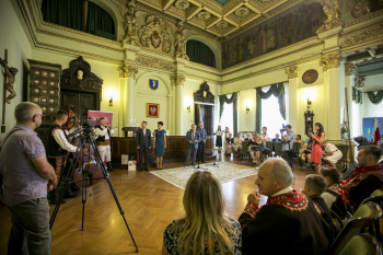 Ludzie siedzą zwróceni do siebie wokół ścian w pomieszczeniu