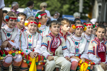 Dzieci w kolorowych strojach siedzą na ławce.