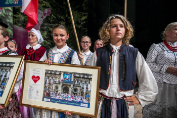 Dziewczynka i chłopczyk w strojach ludowych. Dziewczynka trzyma ramę ze zdjęciem.