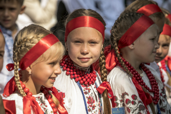 Dziewczynki w warkoczykach i czerwonych wstążkach stoją obok siebie.