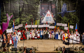 Duża grupa dzieci z tabliczkami stoją na scenie.