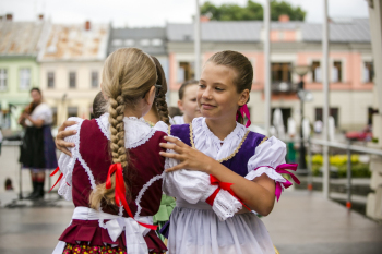 Dwie dziewczynki w strojach ludowych tańczą ze sobą.