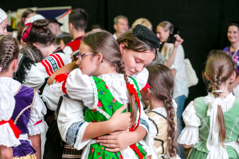 Dziewczynki w strojach ludowych przytulają się.