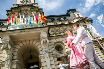 Dziewczynka w różowej sukience i chłopak w białym stroju tańczą przed ratuszem w Nowym Sączu.