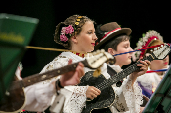 Młodzież w strojach ludowych gra na gitarach.