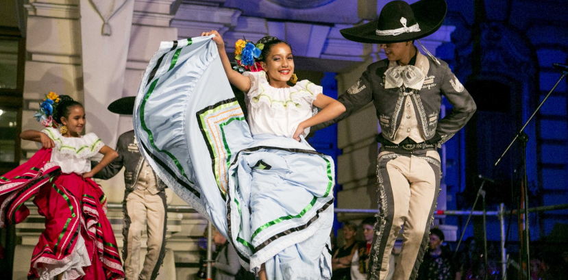Chłopiec i dziewczynka w meksykańskich strojach regionalnych tańczą na scenie